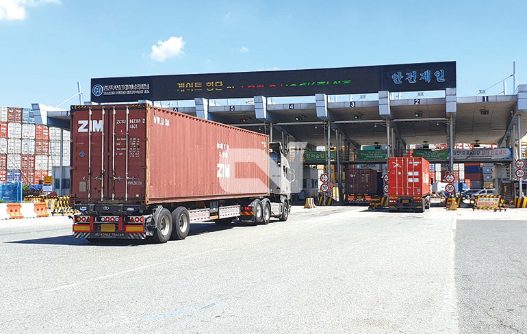 컨테이너 품목을 수송하는 컨테이너 트레일러가 터미널로 들어가고 있는 모습.