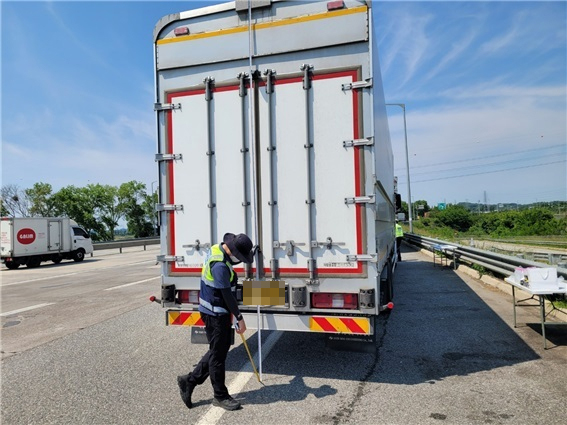 단속원이 상승형 윙바디 화물차의 높이를 측정하고 있다.